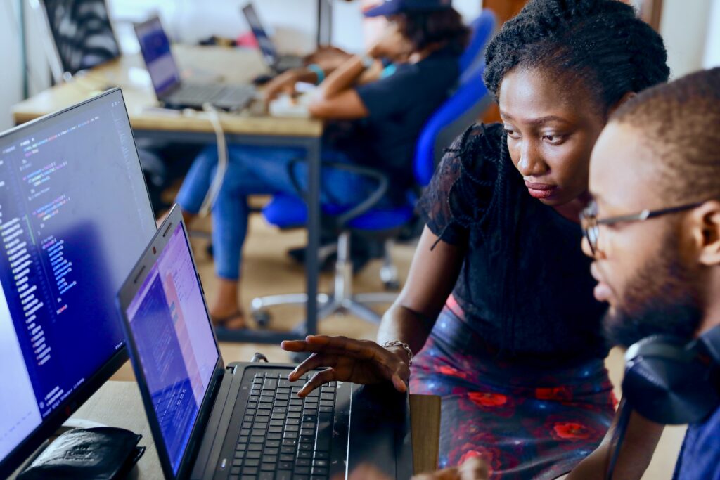 homem sentado em frente ao computador com uma mulher ao lado verificando as informações